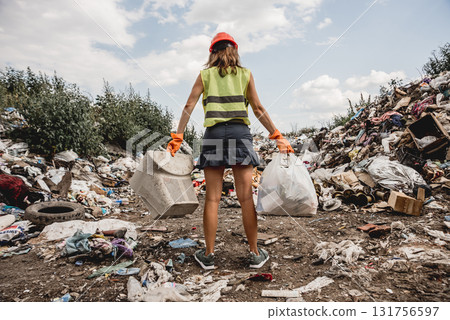 Woman volunteer helps clean the field of plastic garbage. Woman volunteer helps clean the field of plastic garbage. 131756597