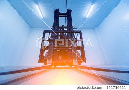Forklift in a large industrial freezer warehouse.  131756611