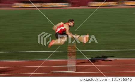 Hurdler in red sprinting and jumping over barrier with motion blur effect Hurdler in red sprinting and jumping over barrier with motion blur effect 131756840