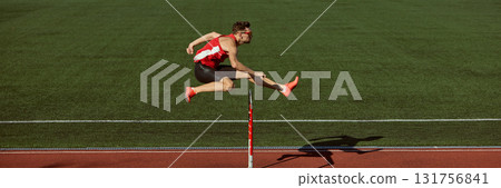 Hurdler jumping over barrier with power and focus during training. Banner Hurdler jumping over barrier with power and focus during training. Banner 131756841