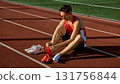 Male athlete putting on red running spikes before training on track field 131756844