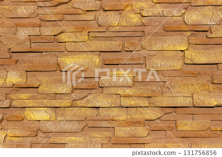 Close up of decorative stone fence made of rectangular textured stones in warm brown and golden tones, ideal for use in architecture, construction, and design backgrounds. Close up of decorative stone fence made of rectangular textured stones in warm brown and golden tones, ideal for use in architecture, construction, and design backgrounds. 131756856