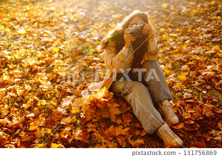 Young woman taking pictures in the autumn forest. Lady Walking In Fall Park With Yellow Foliage. Young woman taking pictures in the autumn forest. Lady Walking In Fall Park With Yellow Foliage. 131756869