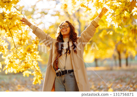 Young woman taking pictures in the autumn forest. Lady Walking In Fall Park With Yellow Foliage. Young woman taking pictures in the autumn forest. Lady Walking In Fall Park With Yellow Foliage. 131756871