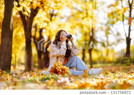 Beautiful woman taking pictures in the autumn forest. Rest, relaxation, tourism, lifestyle concept. 131756872
