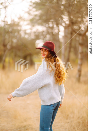 Stylish woman in sweater and hat enjoys autumn nature. People, freedom, lifestyle, travel concept. Stylish woman in sweater and hat enjoys autumn nature. People, freedom, lifestyle, travel concept. 131757030