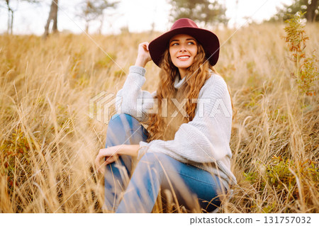 Stylish woman in sweater and hat enjoys autumn nature. People, freedom, lifestyle, travel concept. 131757032