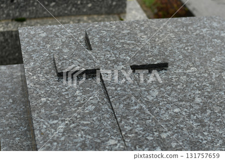 A cross on a black marble slab on a grave in a cemetery 131757659