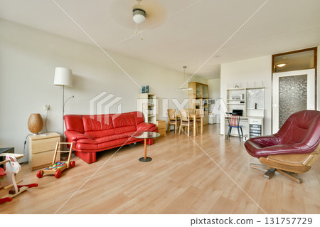 A contemporary living space featuring a red sofa, stylish chair, and minimalist decor, creating a comfortable and inviting atmosphere. A contemporary living space featuring a red sofa, stylish chair, and minimalist decor, creating a comfortable and inviting atmosphere. 131757729