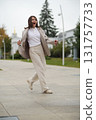 A mature woman gleefully spins on a sidewalk, enjoying the moment in her stylish outfit. The image encourages embracing life fully, regardless of age or societal expectations. 131757733