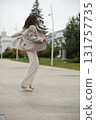 A woman walks and spins freely on an urban path, arms outstretched in joyful motion. This candid moment reflects emotional liberation, independence, and the beauty of aging with vitality. 131757735