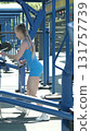 Exercising with dumbbells, a woman in a blue bodysuit engages in strength training at an outdoor gym. The image showcases the combination of weight training and the fresh air benefits of outdoor 131757739