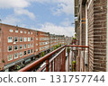 A beautiful urban landscape captured from a balcony, showcasing classic architecture and a lively street, framed by a clear sky and charming facades. 131757744