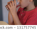 A young boy in a red shirt quenches his thirst with a glass of water, a subtle reminder of the importance of staying hydrated. Perfect for promoting health and hydration. 131757745