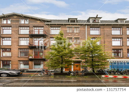An aesthetically pleasing modern apartment building showcasing balconies and lush trees situated in an urban environment, complemented by parked bicycles. 131757754