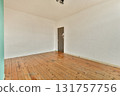 A spacious interior featuring wooden flooring and a plain wall with a door. The simplicity of the design creates a calm and inviting atmosphere. 131757756