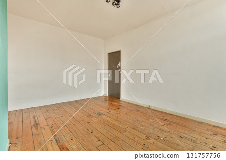 A spacious interior featuring wooden flooring and a plain wall with a door. The simplicity of the design creates a calm and inviting atmosphere. A spacious interior featuring wooden flooring and a plain wall with a door. The simplicity of the design creates a calm and inviting atmosphere. 131757756