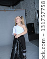This cool young girl rocks a black leather jacket over a chic pleated skirt and lace socks, pairing it with a confident pose. Her fun and rebellious style channels rockstar energy, ideal for modern 131757758