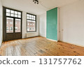 An empty room featuring wooden flooring and large windows that allow ample natural light. The simple design highlights the potential for various decor styles. 131757762