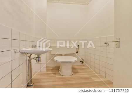 A clean and minimalistic bathroom showcasing white tiled walls, a simple toilet, and modern plumbing fixtures in a compact space. 131757765