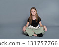 A girl poses casually while sitting on the ground with relaxed posture. The image reflects authentic youth moments often linked to emotional development and self-expression. 131757766