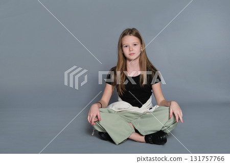 A girl poses casually while sitting on the ground with relaxed posture. The image reflects authentic youth moments often linked to emotional development and self-expression. 131757766