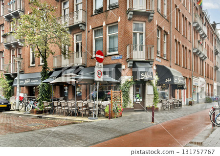 A cozy cafe with outdoor seating nestled within a brick building, surrounded by vibrant greenery and bustling city life. 131757767