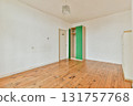 A bright, minimalist room featuring wooden flooring and simple decor. The walls are mostly white with a touch of green in the wardrobe area, providing a calm and spacious feel. 131757768