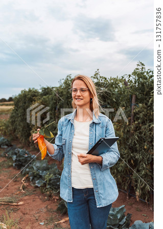 Female agronomist inspecting vegetables with tablet in a field Female agronomist inspecting vegetables with tablet in a field 131757836