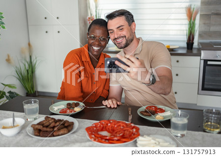 Interracial couple taking a selfie while having lunch in the kitchen 131757913