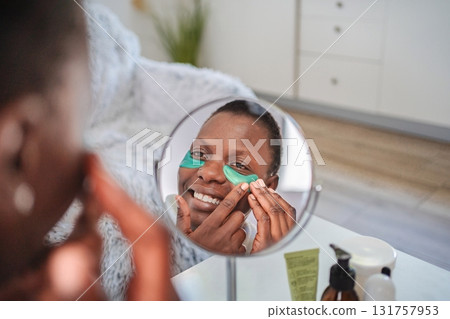 Smiling woman applying anti-aging under eye patches at home Smiling woman applying anti-aging under eye patches at home 131757953