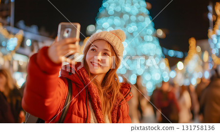 A smiling woman taking a selfie with her smartphone among Christmas lights A smiling woman taking a selfie with her smartphone among Christmas lights 131758136