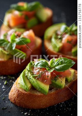 Delicious avocado and tomato toast topped with fresh basil on dark background Delicious avocado and tomato toast topped with fresh basil on dark background 131758778