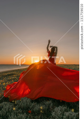 Sunset Dress Woman: Woman in red dress dances at sunset near sea, celebrating freedom, joy. Sunset Dress Woman: Woman in red dress dances at sunset near sea, celebrating freedom, joy. 131759010
