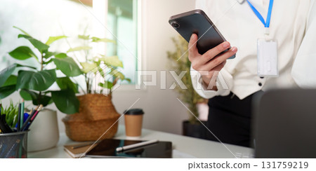 Mobile Communication. Woman holding smartphone in modern office. Mobile Communication. Woman holding smartphone in modern office. 131759219