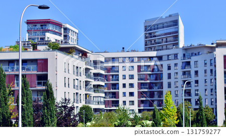 A residential building by lush green trees and surrounded by fresh vegetation on a clear sunny day. Modern architecture residential apartment building complex surrounded by greenery. A residential building by lush green trees and surrounded by fresh vegetation on a clear sunny day. Modern architecture residential apartment building complex surrounded by greenery. 131759277