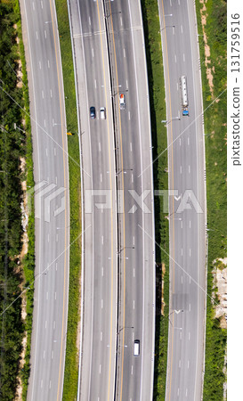 Drone shot aerial view multiple highway lanes in Thailand with few vehicles. Clean asphalt, green roadside, and minimal traffic convey efficiency and motion Drone shot aerial view multiple highway lanes in Thailand with few vehicles. Clean asphalt, green roadside, and minimal traffic convey efficiency and motion 131759516