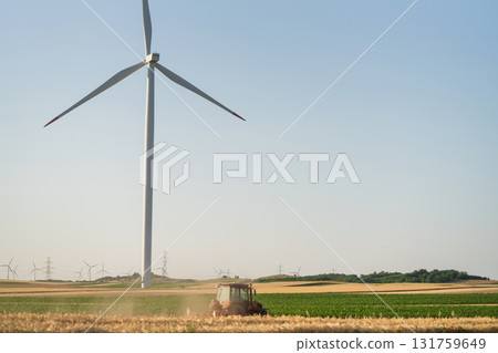 Agricultural tractor is working on the field with wind turbines Agricultural tractor is working on the field with wind turbines 131759649