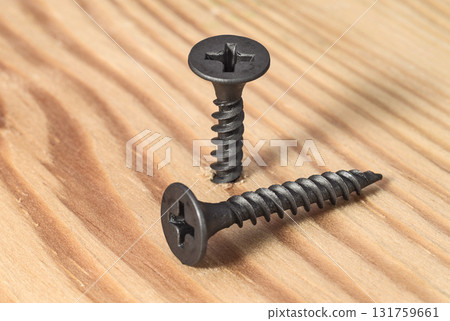 Black screws on the wooden surface close up 131759661