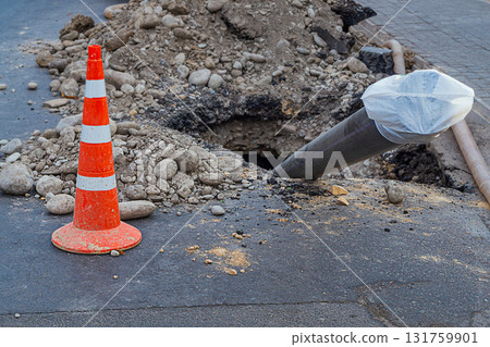 Construction site for laying of underground utilities using the technology of horizontal directional drilling under asphalt. Black plastic pipe made of low-pressure polyethylene sticks out of ground Construction site for laying of underground utilities using the technology of horizontal directional drilling under asphalt. Black plastic pipe made of low-pressure polyethylene sticks out of ground 131759901