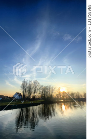 Breathtaking Sunset Reflections Glimmering over Tranquil Water and Picturesque Landscape 131759969