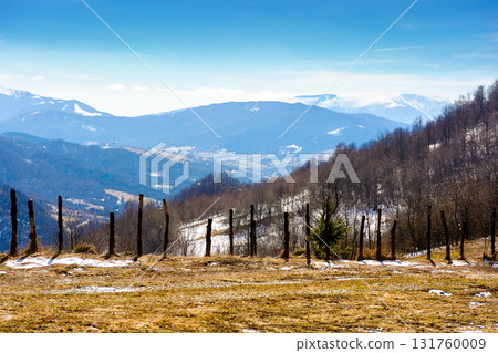 mountainous countryside on a sunny day. winter to spring season change scenery. melting snow and leafless trees on the rolling hills. view in to the distant valley of transcarpathia, ukraine mountainous countryside on a sunny day. winter to spring season change scenery. melting snow and leafless trees on the rolling hills. view in to the distant valley of transcarpathia, ukraine 131760009