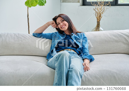 Portrait of relaxed beautiful smiling brunette woman sitting on sofa in living room 131760088