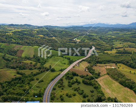 Aerial drone view of Highway winding through lush green mountains between Nan, Thailand. A scenic landscape of the road surrounded by tropical forest and a peaceful countryside 131760269