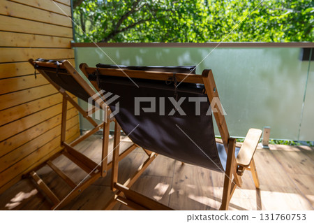 Deck chairs, wooden balcony, nature view from a sunny modern terrace offering peaceful outdoor relaxation. 131760753