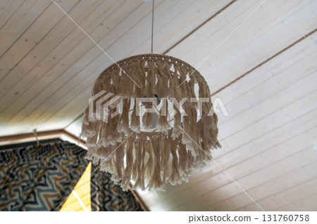 Macrame lamp, wooden ceiling, bohemian decor, stylish pendant light fixture hangs from white slatted planks creating a cozy home atmosphere Macrame lamp, wooden ceiling, bohemian decor, stylish pendant light fixture hangs from white slatted planks creating a cozy home atmosphere 131760758