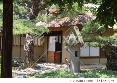 A Japanese garden with an old thatched roof house and a stone lantern A Japanese garden with an old thatched roof house and a stone lantern 131760976