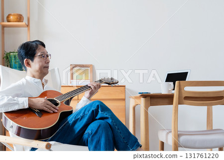 Middle-aged man playing guitar in the living room 131761220