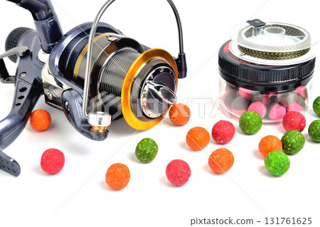 Fishing coil, colored boilies, braided cord, on white background, close-up 131761625