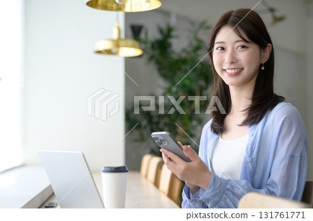 有一個智能手機的一名婦女在咖啡館 有一個智能手機的一名婦女在咖啡館 131761771
